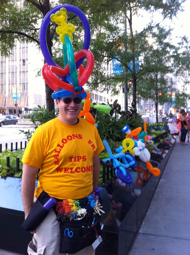 Scott Green in a yellow shirt and an enormous balloon hat, making balloon animals on Michigan Avenue