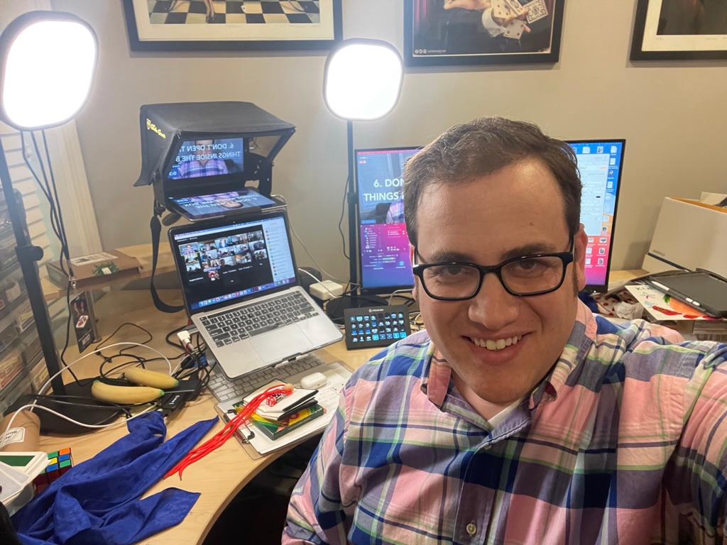 Scott Green smiling in his home studio, surrounded by lights, screens and props for a virtual show