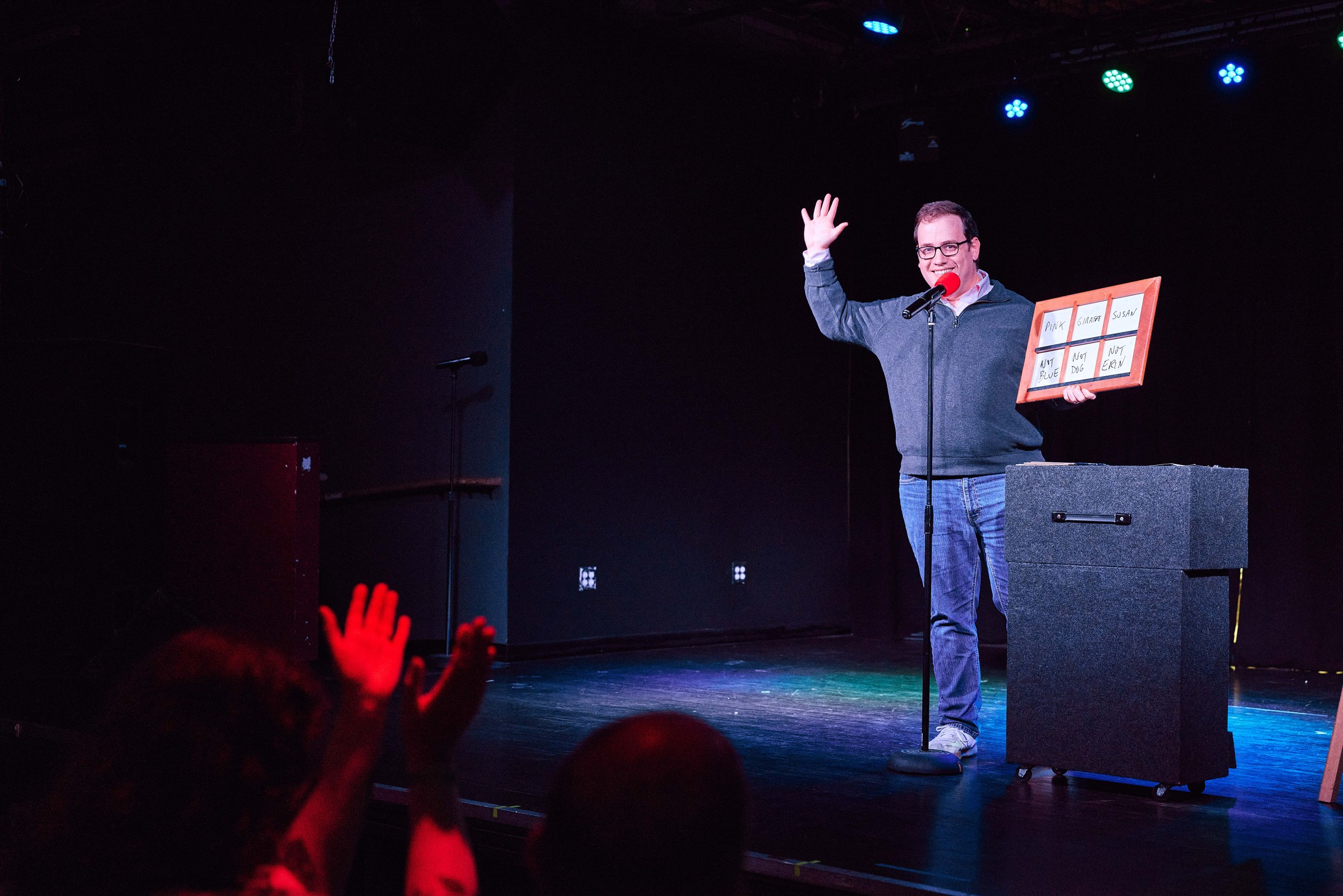 Scott Green waving to the audience at a comedy show in Madison